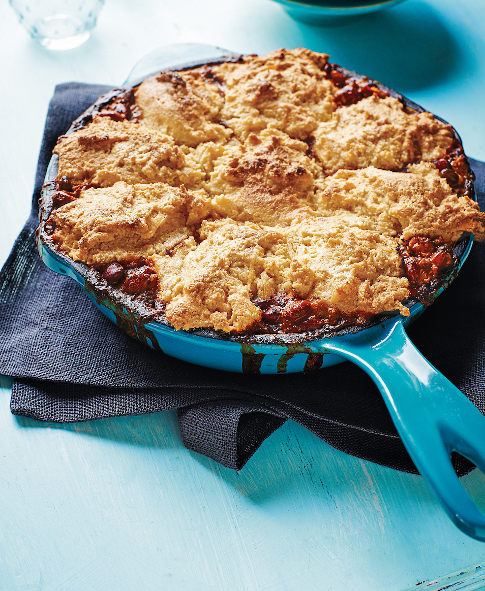 A skillet of crispy Chili Cornbread Pot Pie resting on a kitchen towel.