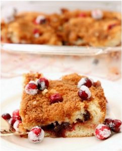 A slice of Cranberry Cinnamon Coffee Cake topped with sugared cranberries.