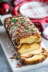 A loaf of Gluten Free Eggnog Crumb Cake with a slice cut on a white platter.