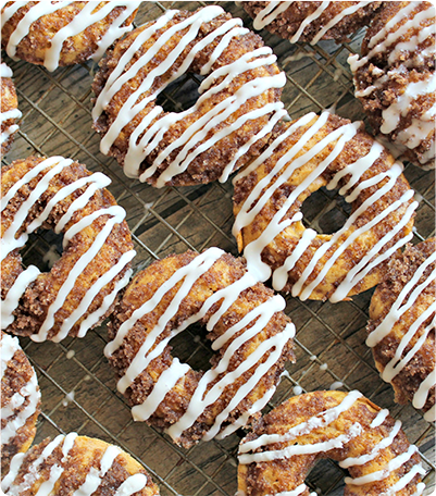 Several Pumpkin Crumb Doughnuts with Brown Butter Frosting resting on a cooling rack.