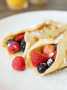 Two Buttermilk Crepes filled with raspberries, strawberries, blueberries, blackberries and topped with powdered sugar.