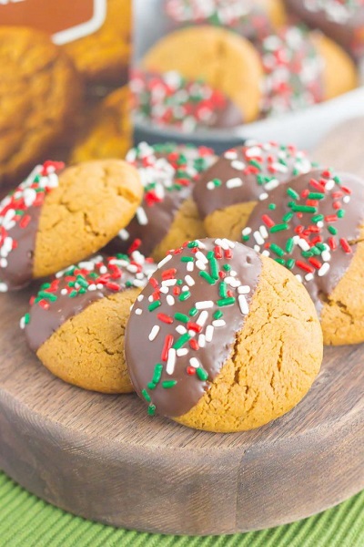 Several Dark Chocolate Dipped Gingerbread Cookies topped with holiday sprinkles on a platter.