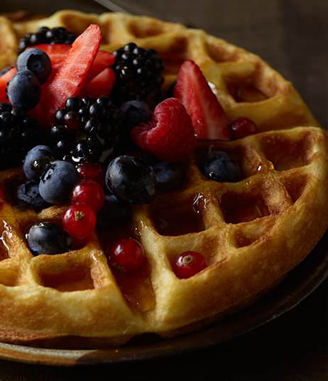 A Buttermilk Waffle topped with blueberries, cranberries, strawberries, raspberries, blackberries and syrup.