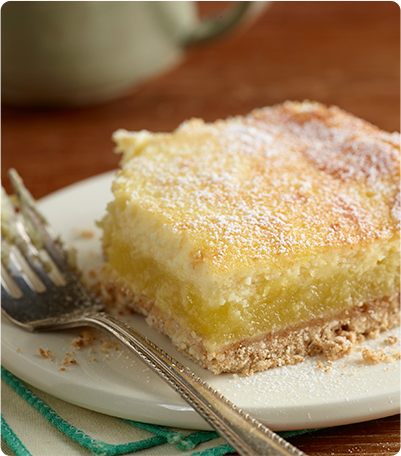 A Meyer Lemon Cheesecake Bar with a small bite taken out of it.