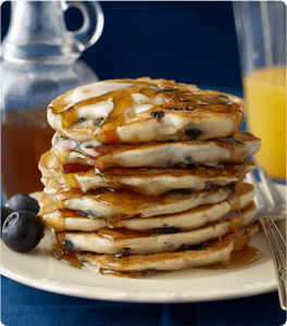 A stack of Apple Blueberry Pancakes topped with syrup.