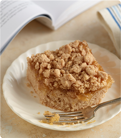 A slice of Apple Crumb Bar on a white plate with a silver fork.