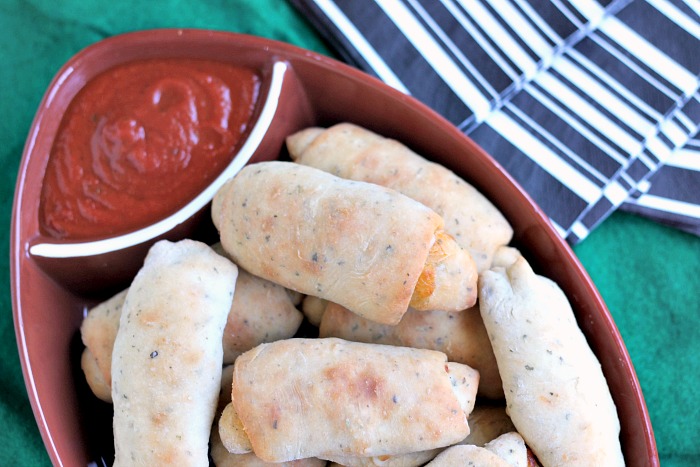 A platter of Pepperoni Flatbread Roll-ups with a side of marinara sauce.