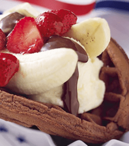 A chocolate Banana Split Waffle topped with banana, strawberries and chocolate sauce.