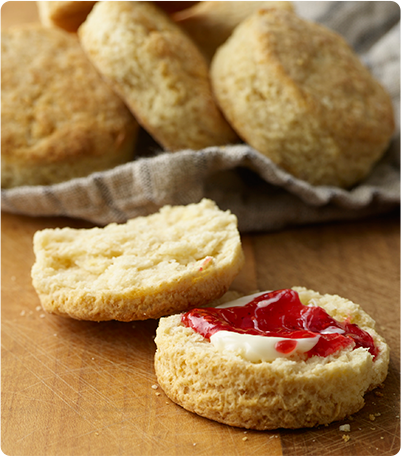 A Buttermilk Biscuit sliced in half with one side slathered with jelly and cream.