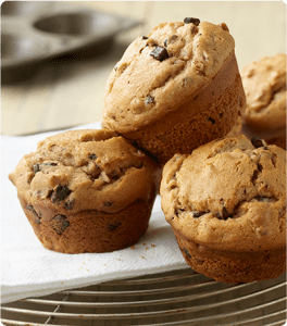 A stack of fresh-baked Chocolate Chunk Nut Muffins on a serving dish.