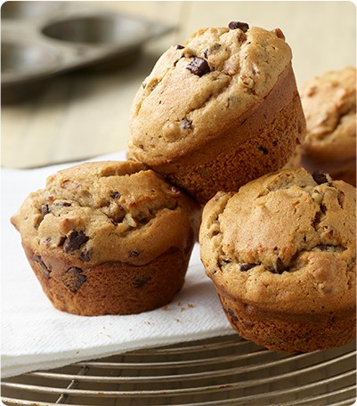 A stack of fresh-baked Chocolate Chunk Nut Muffins on a serving dish.
