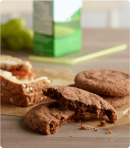 Two halves of a Chocolate Snickerdoodle stacked on top of each other in front of other cookies and a half-eaten sandwich.