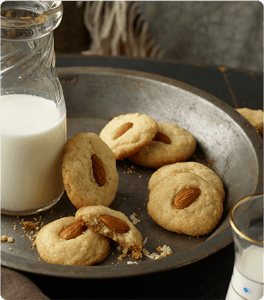 Several Coconut Cookie Chews on a platter with a jar of milk.
