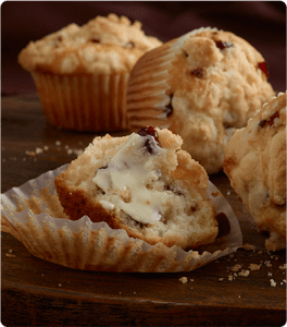 A fresh-baked Cranberry Streusel Muffin with butter spread on it.