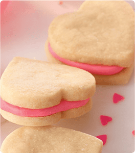 Three Easy Valentine Sandwich Cookies garnished with heart-shaped sprinkles.