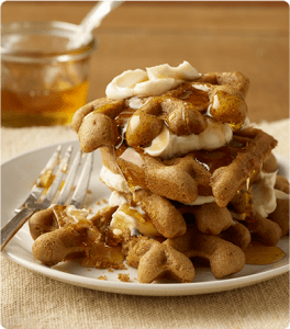 A stack of Gingerbread Waffles topped with butter and syrup.