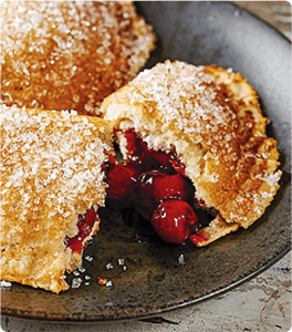 A Gluten Free Pancake Turnover cut in half on a brown plate.