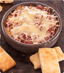 A bowl of Hot Reuben Dip topped with melty cheese.