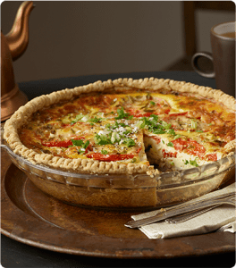 A Gluten Free Pie Crust filled with an egg and vegetable mixture in a glass pie dish.