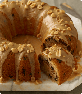 A Peanut Butter Fluted Cake topped with a peanut butter glaze and chopped peanuts.