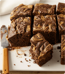 Fresh slices of Peanut Butter Swirl Snack Cakes on a cutting board.