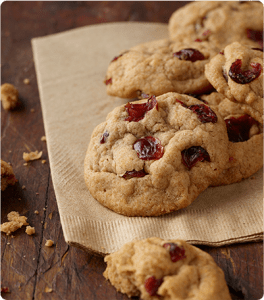 Pumpkin and Cranberry Cookies sit on a napkin on a wooden table.