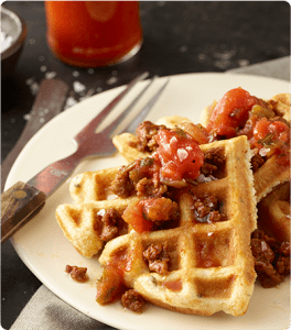 A plate of Santa Fe Waffles topped with salsa and chorizo.