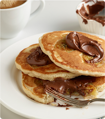 A stack of Sautéed Banana Pancakes topped with gluten free chocolate hazelnut spread.