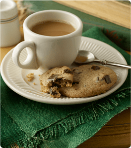 A plate of Triple Chocolate Chunk Banana Cookies paired with a cup of coffee.