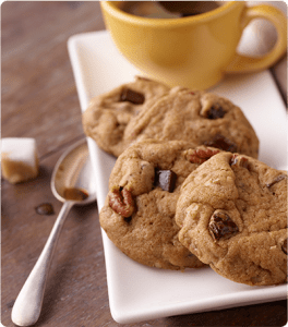 A plate of Triple Chocolate Chunk Nut Cookies paired with a cup of coffee.