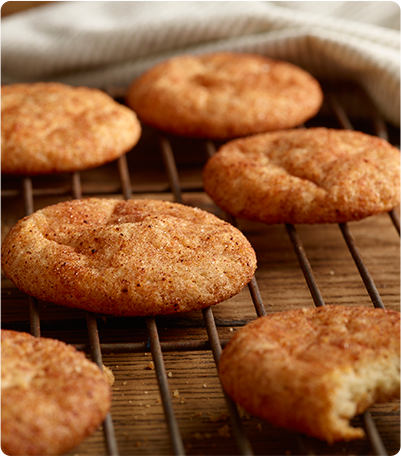 Several Zesty Snickerdoodles cookies cooling on a baking rack.
