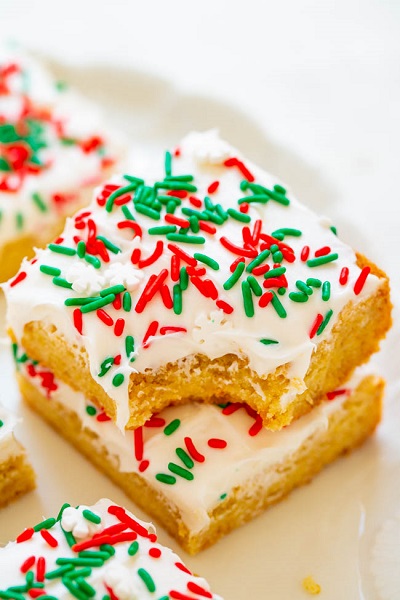 A plate of Snickerdoodle Bars with Cream Cheese Frosting and white, green and red sprinkles.