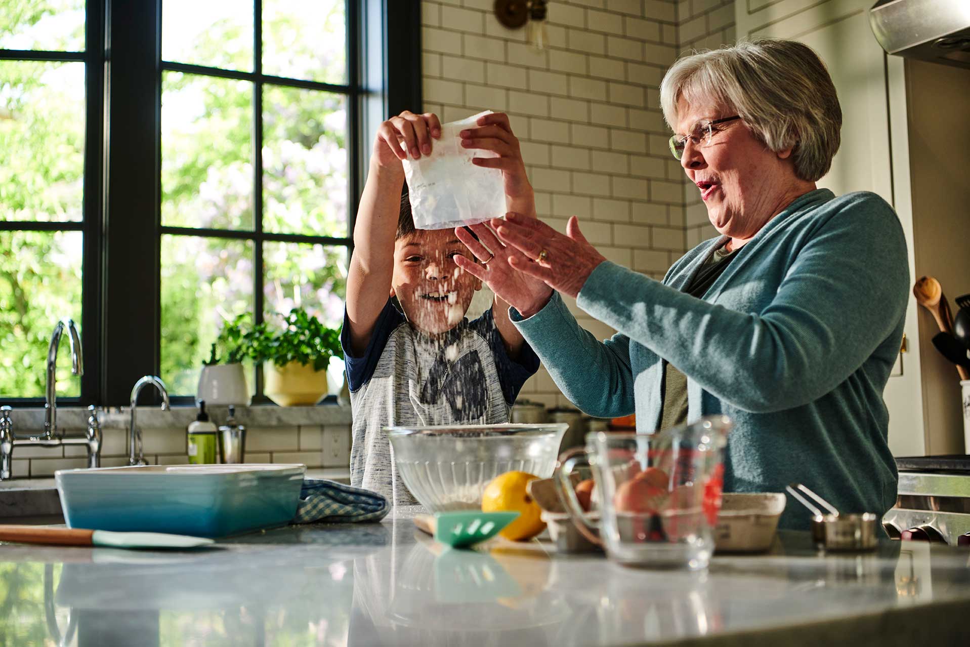 Grandparent and grandchild pouring Meyer Lemon Bar mix into a mixing bowl and having fun in the kitchen.