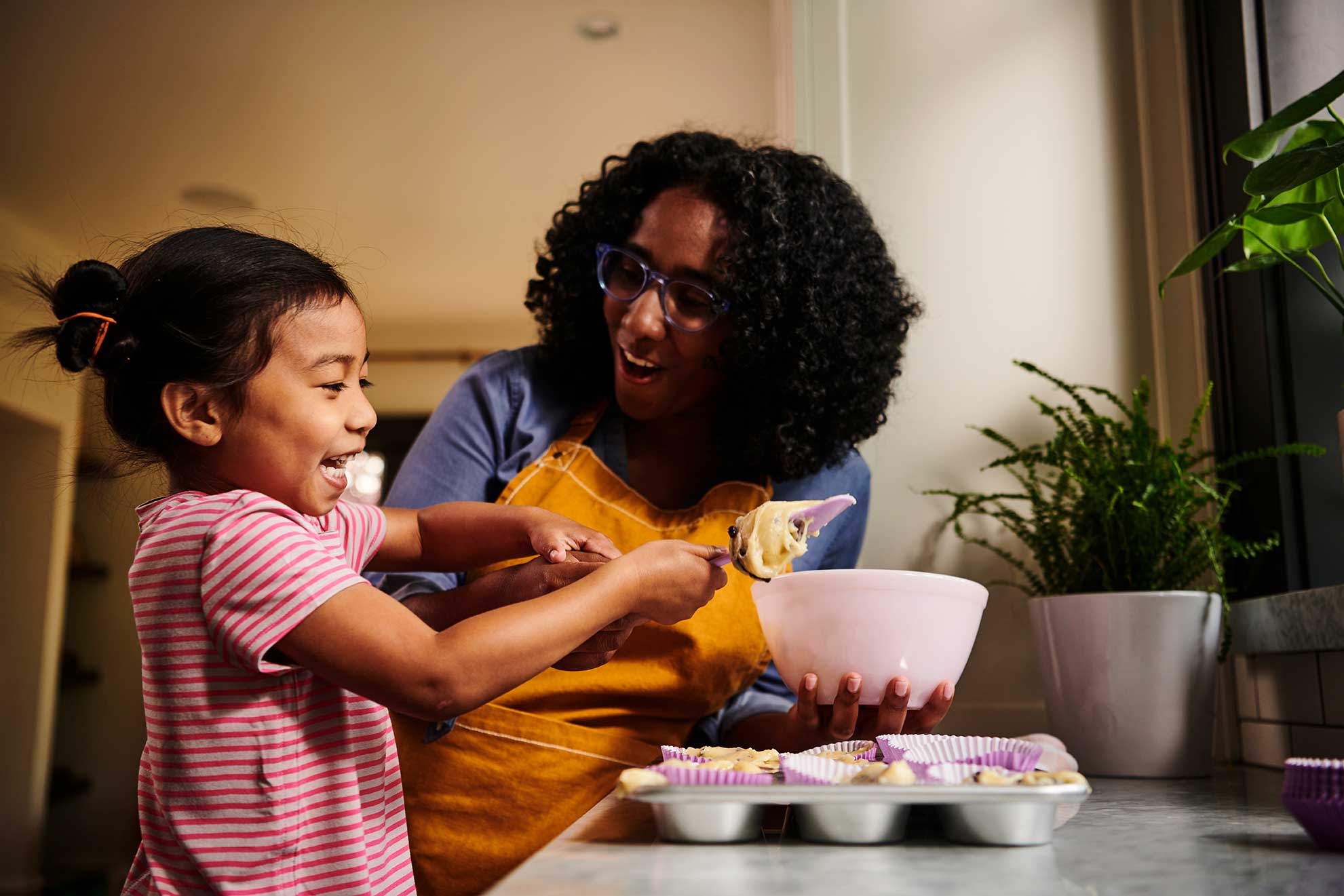 Woman and child having fun in the kitchen baking muffins.