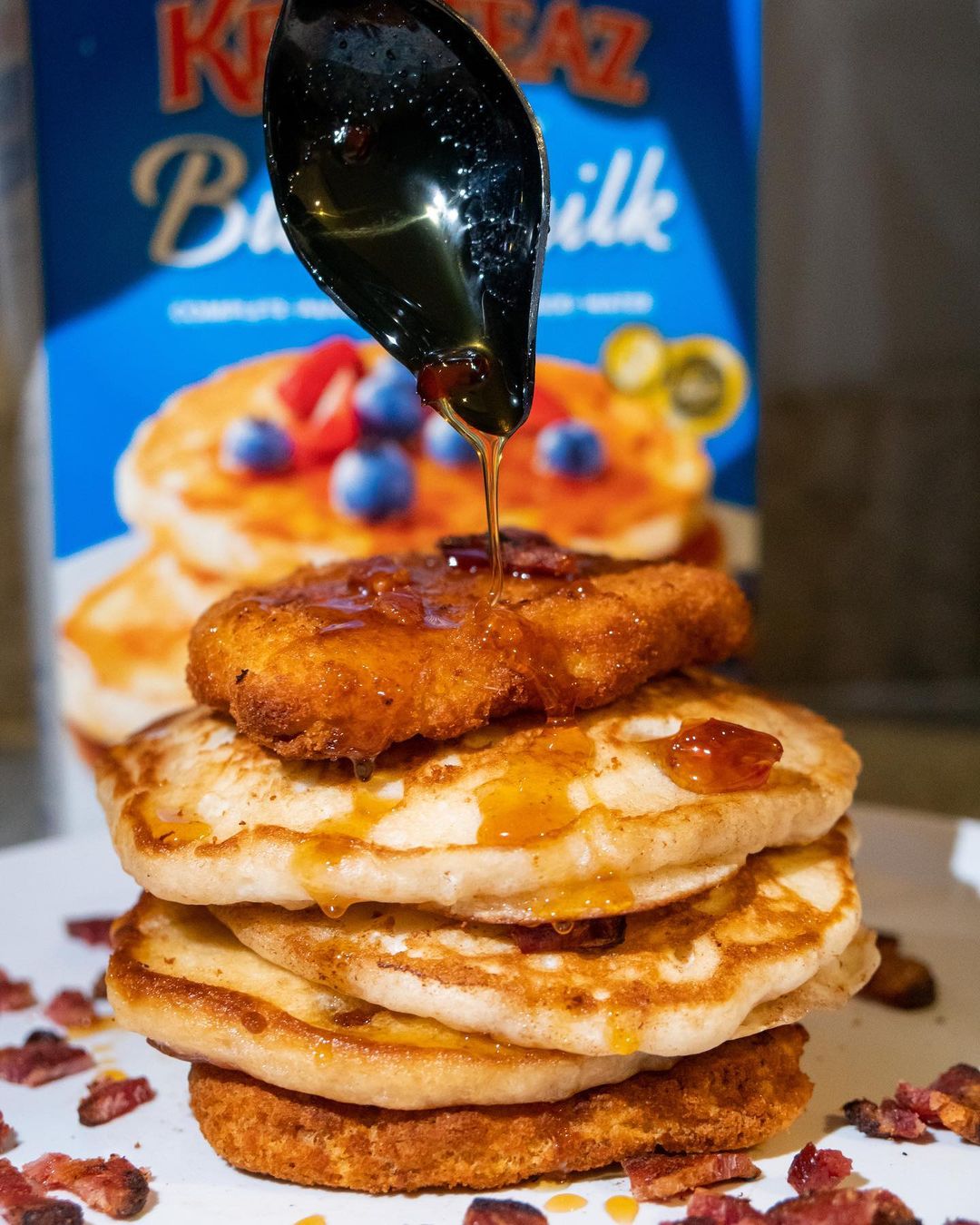 A stack of buttermilk pancakes nestled between two chicken breasts and topped with a hot honey maple syrup drizzle.