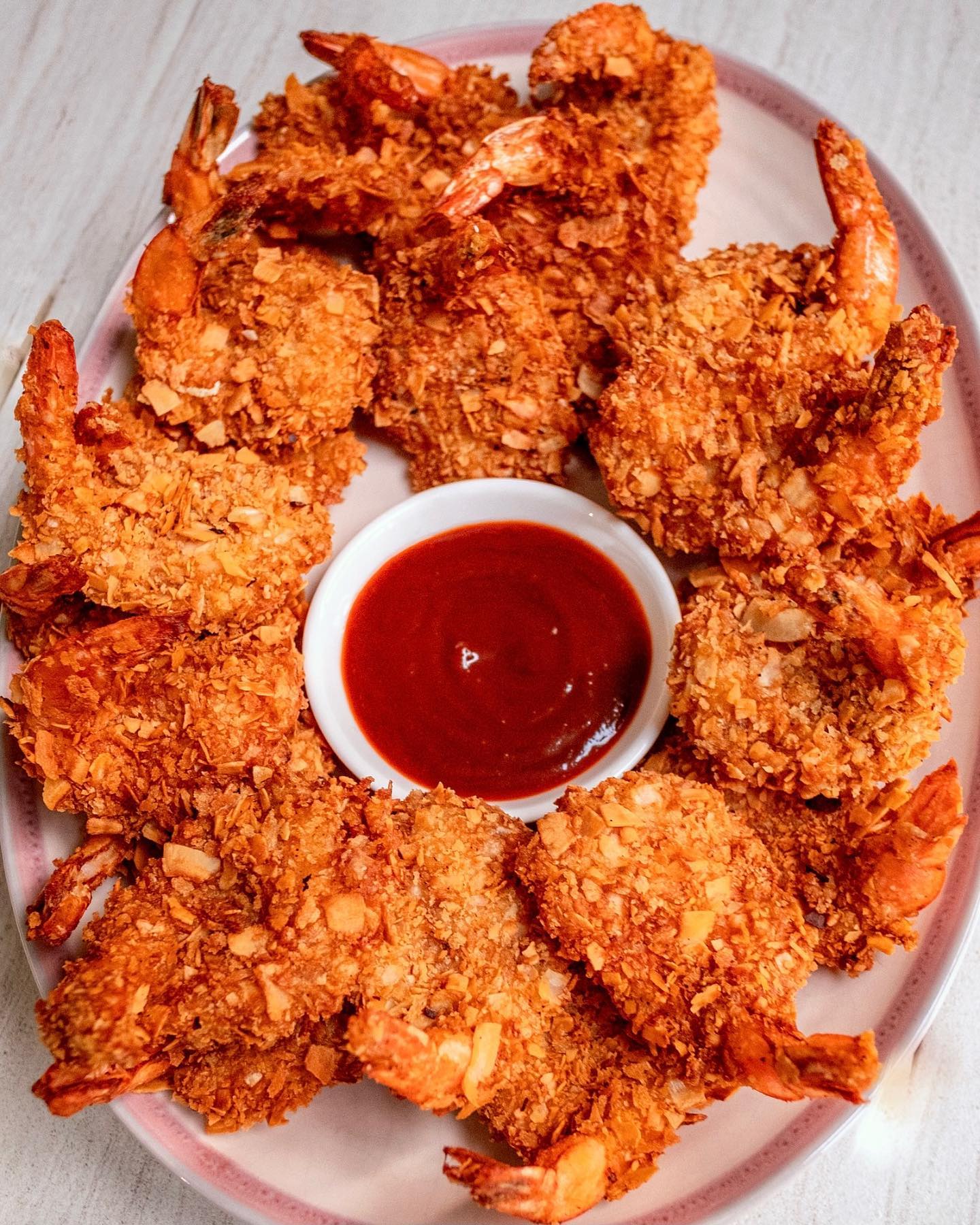 A platter of Coconut Shrimp served with a dipping sauce.