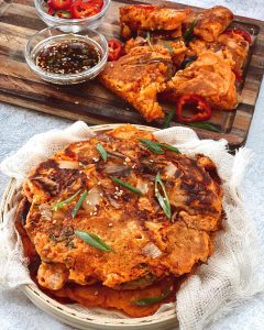 A stack of Kimchi Pancakes garnished with herbs.