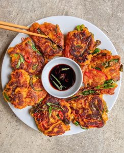 A plate of Hot Pajeon Pancakes served with a homemade dipping sauce and chopsticks.