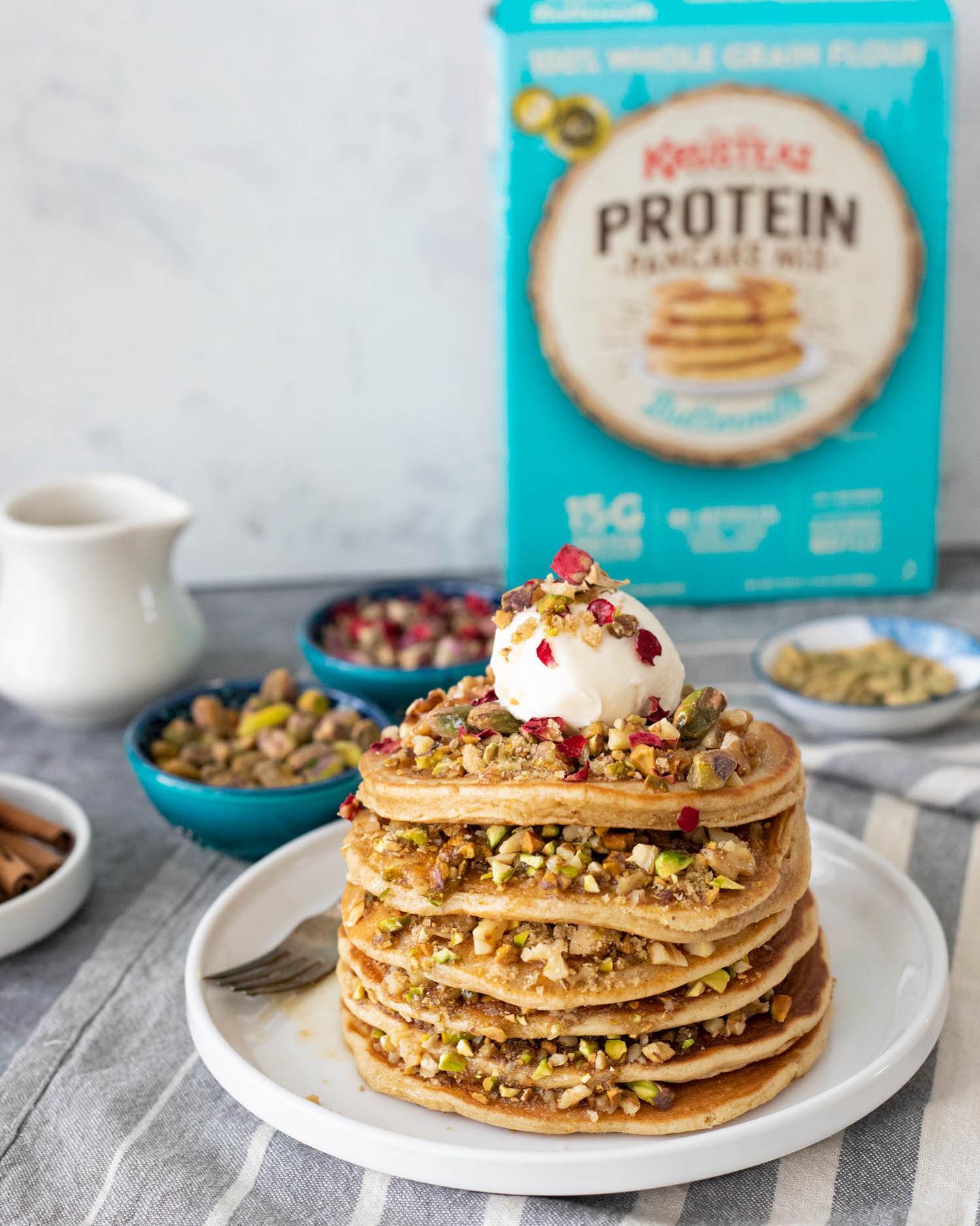 A stack of Baklava Pancakes topped with walnuts, pistachios, honey and vanilla ice cream.