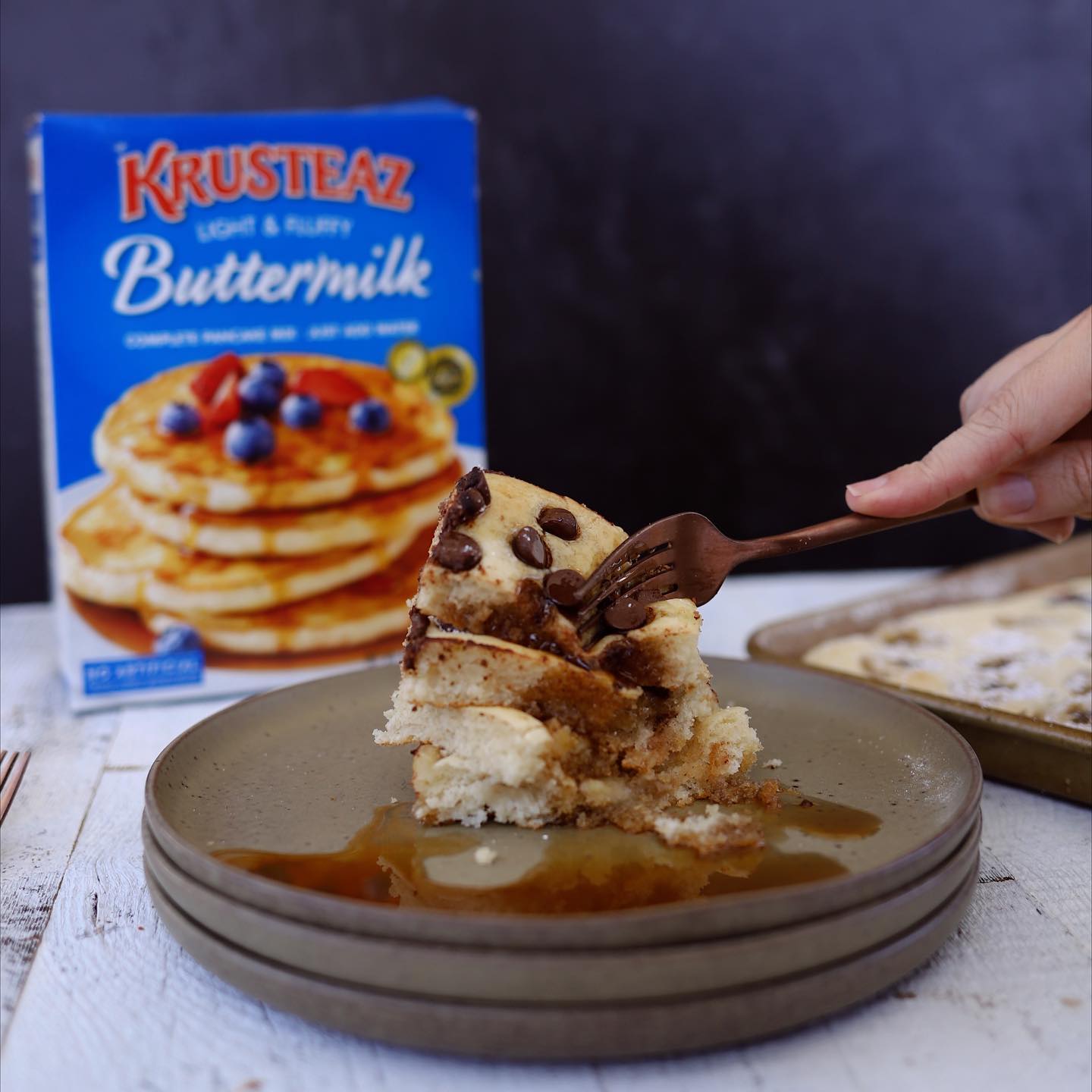 A person takes a fork to a stack of sheet pan pancake slices, made with Krusteaz Buttermilk Pancake mix.
