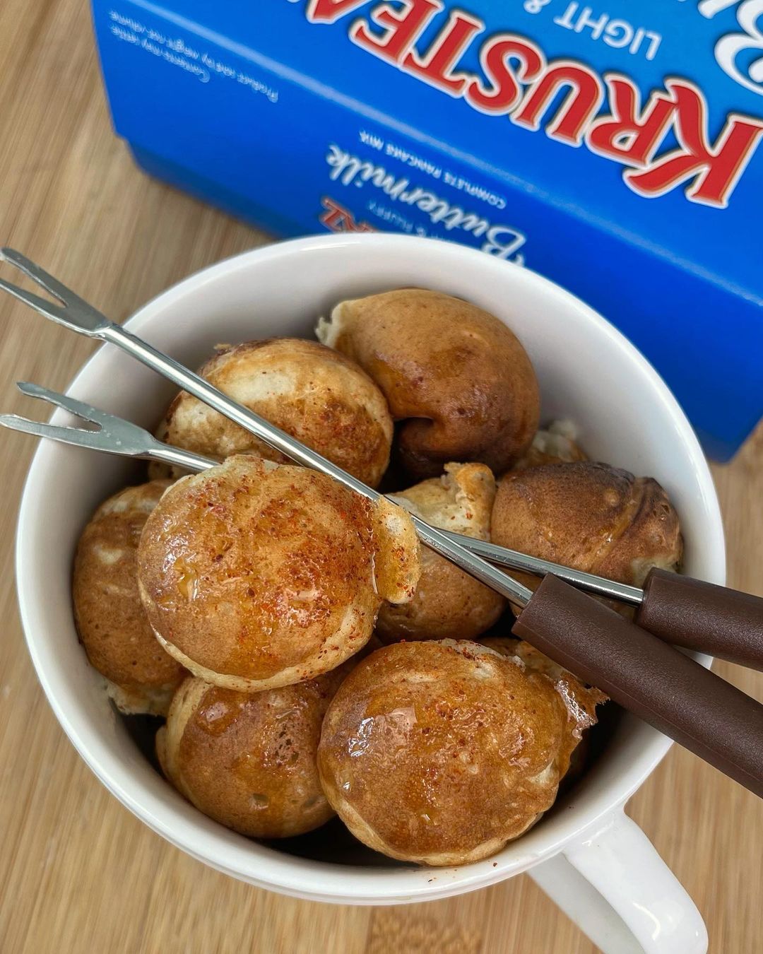 A coffee mug of Chicken Pancake Bites with two skewers laying across the top.