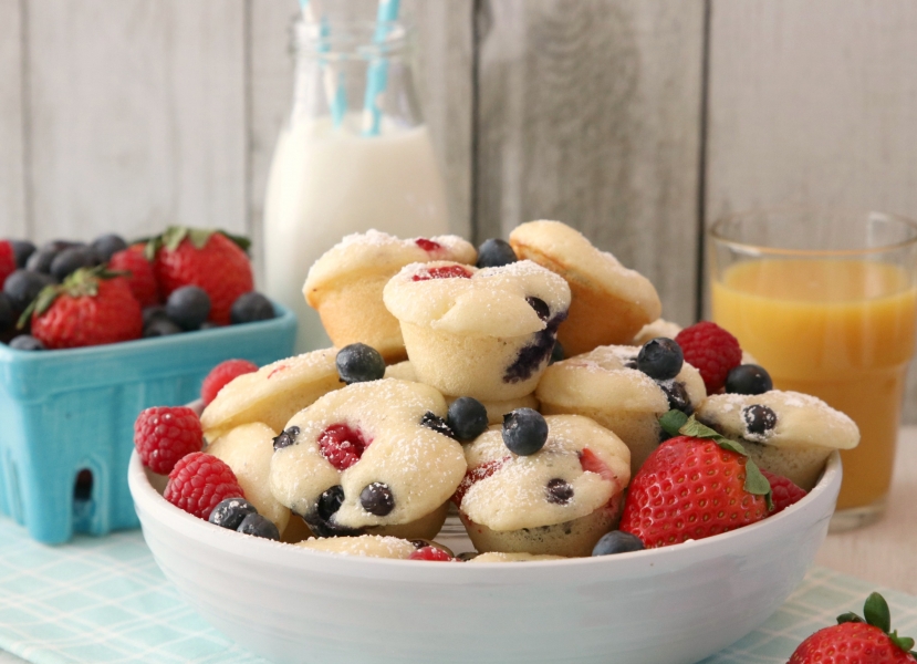 A bowl full of Berry Protein Pancake Bites, fresh strawberries and blueberries.