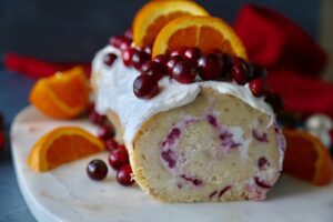 A Cranberry Orange Roulade garnished with cranberries and orange slices.