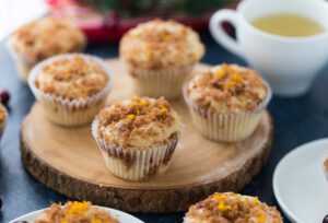 Four Cranberry Orange Swirl Muffins on a decorative wooden board.