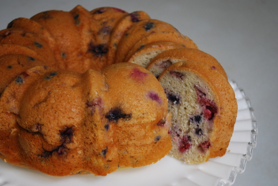 A Mixed Berry Bundt Cake on a paper plate with a slice cut out.
