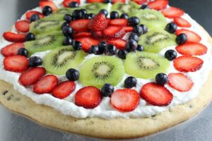 A Fruit Pizza Pancake topped with sliced strawberries, kiwi and blueberries.