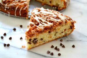 A slice of Chocolate Chip Crumb Cake with Vanilla Bean Glaze garnished with chocolate chips.