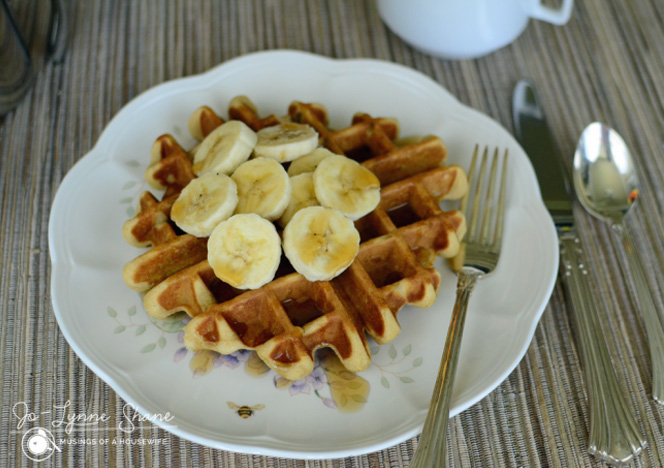 A Banana Waffle with Peanut Butter Syrup and banana slices on a plate.