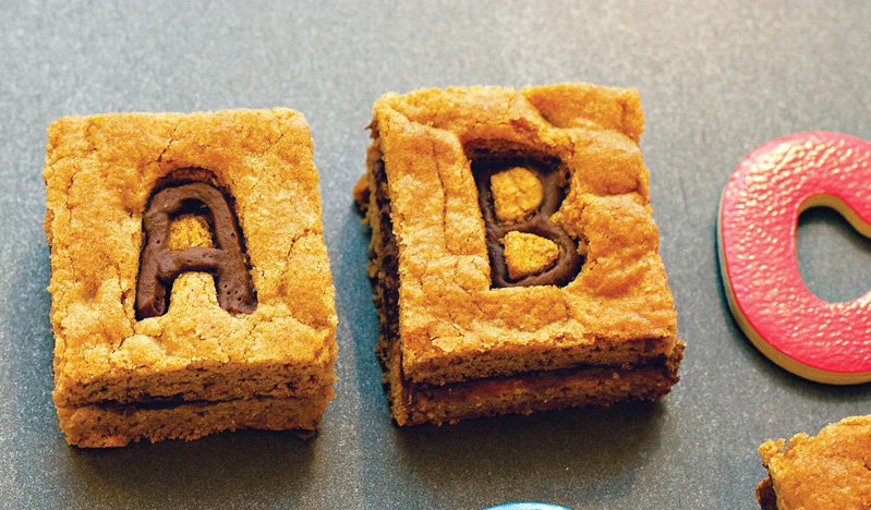 Two fresh-baked alphabet cookie bars sit on a table.