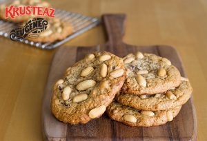 Four Post Workout Peanut Butter & Banana cookies sit on a wooden cutting board.